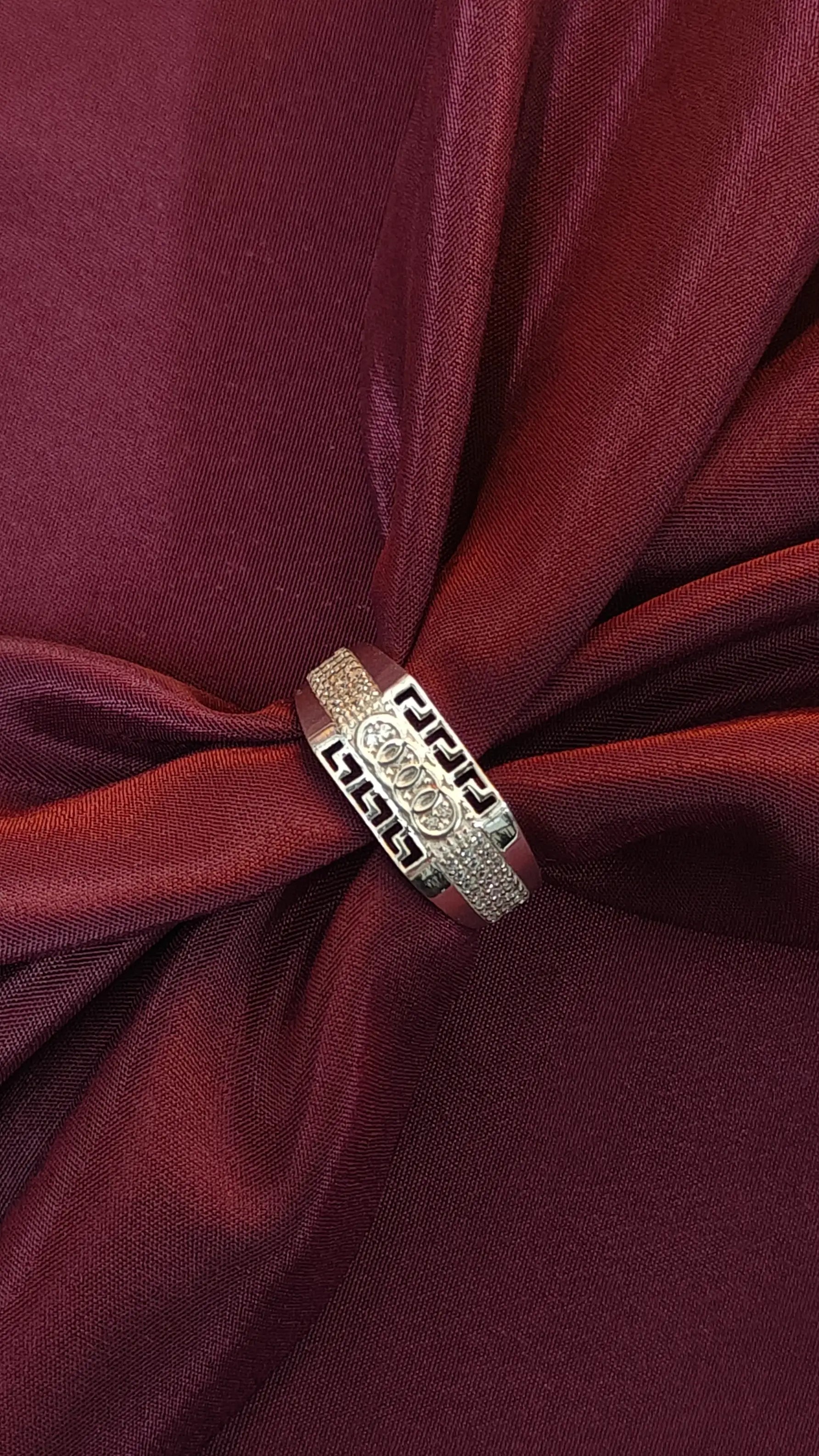 Silver ring with intricate design on a red fabric background